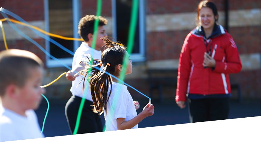 Group of young people and teacher taking part in activity with ribbons in an outdoor playground
