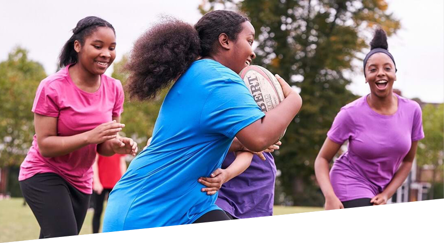 Group of teenage girls having fun playing rugby outdoors