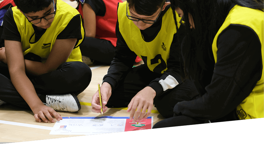 Group of young people sat on the floor working on a problem together